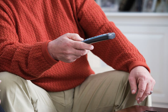 Midsection of a man holding a remote control