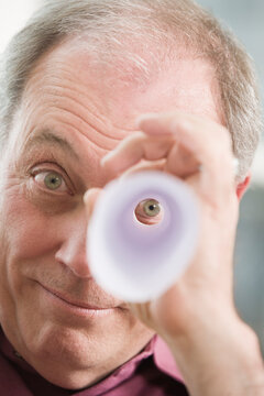 Portrait of a mature man peeping through rolled up paper