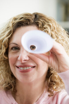 Portrait of a mature woman peeping through rolled up paper