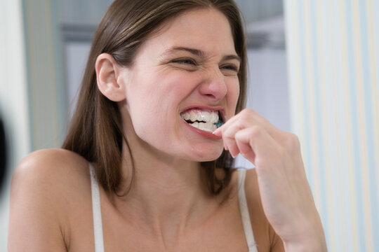 A young woman brushing her teeth in front of mirror