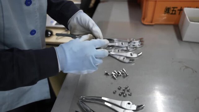 Worker assembling pliers by hand inserting pivot bolt and nut at quality inspection table