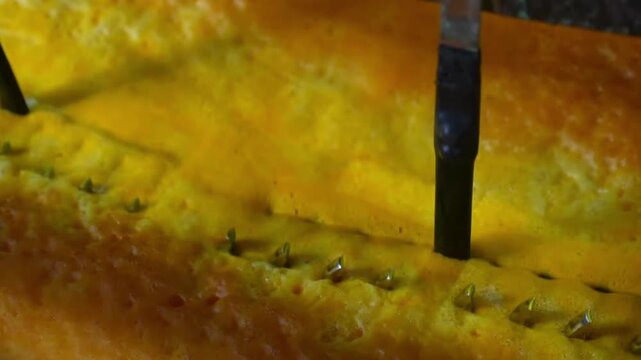 Close-up of pliers handles dipping into yellow chromate passivation chemical bath