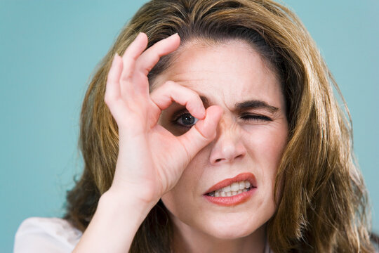 Close-up of a mid adult woman looking through a circle formed by her fingers