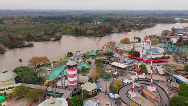 Aerial view of amusement park rides and visitors near riverbank in Argentina