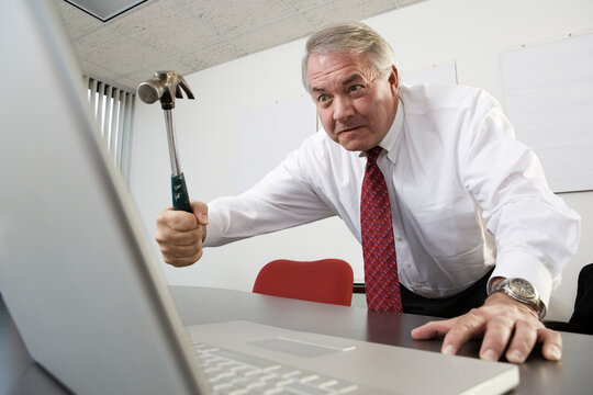 View of a business man trying to hit a laptop