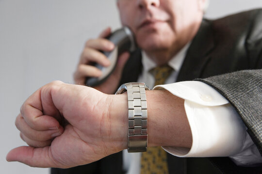 View of a business man checking time and using an electronic shaver on the job