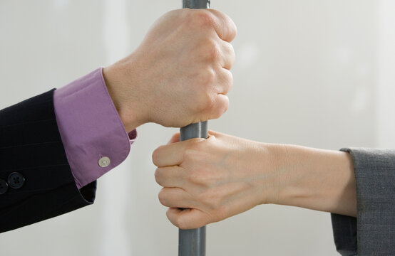Close-up of a man and a woman's hands gripping the rod of a scaffolding