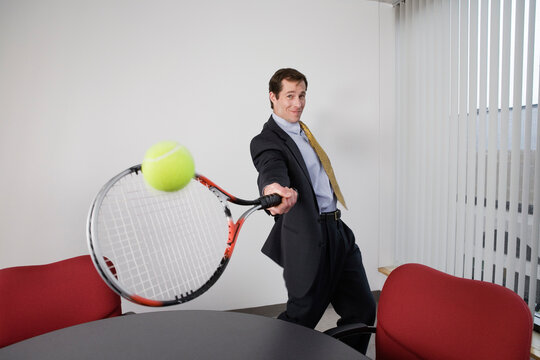 Portrait of a businessman playing tennis in an office