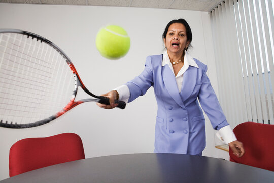 Portrait of a businesswoman playing tennis in an office