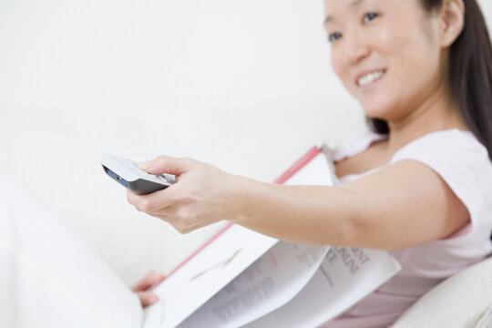 Young woman using a TV remote control