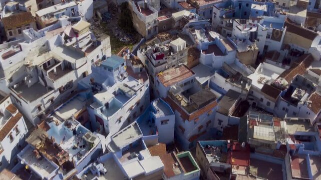 Drone tilts over Chefchaouen's white and blue rooftops ascending the hill