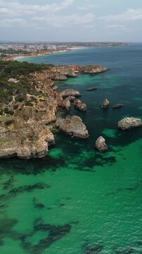 Vertical camera pans left over Ponta Jo&atilde;o de Arens and reveal Praia do Valentim do Carvalho, showing cliffs and turquoise water