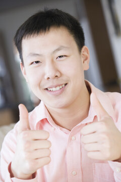 Portrait of a teenage boy making thumbs up gesture with his both hands
