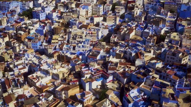 Overhead drone pan reveals Chefchaouen blue medina rooftop mosaic in Morocco.