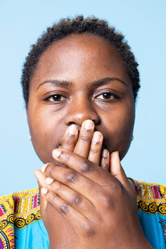 African American woman covering her mouth in front of the camera, being silent and recreating three wise monkeys symbol, female model showing motivational sign and wisdom in studio