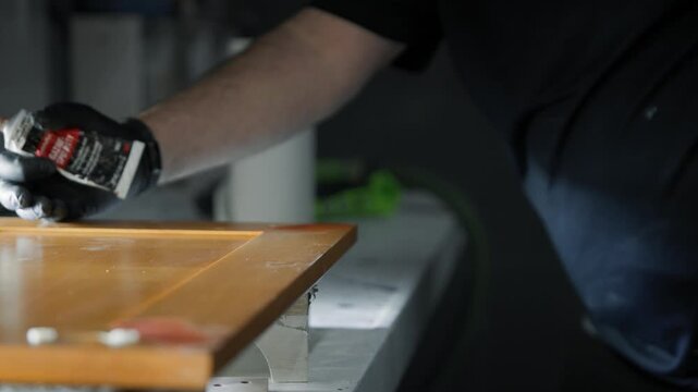 Close-up of a woodworker repairing cabinet scratches with putty and a spackling knife, ideal for woodworking, restoration, and home improvement projects.