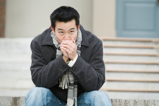 Close-up of a young man blowing his hands to keep warm in winter