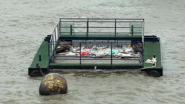 Automated river garbage collector boat catching floating plastic waste and trash on water surface. Genuine footage