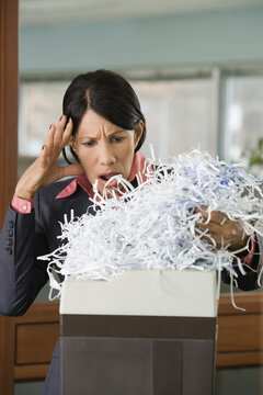 Businesswoman looks at shredded documents in shock