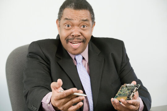 Portrait of a businessman holding a computer chip and a pen