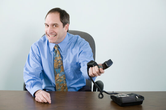 Portrait of a businessman holding a telephone receiver and smiling