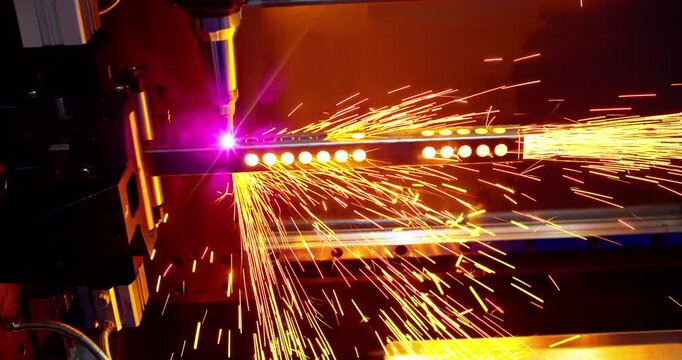 Close-up of a laser cutting machine processing a metal profile with sparks flying. Cinematic shot of CNC laser cutter machine working on steel profile in modern factory.