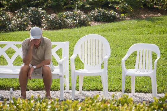 Senior man sitting on a bench with his hand on his chin