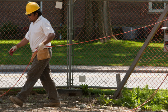 Construction worker laying power cord at a construction site