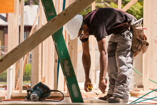 Carpenter measuring with a tape measure at a construction site