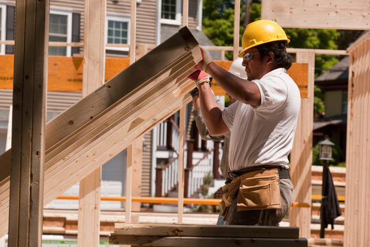 Carpenter lifting wall framing at a construction site
