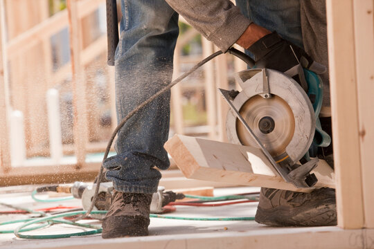 Carpenter sawing a plank at a construction site