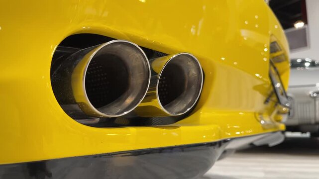 Marvel at the striking details of a yellow sports car's exhaust as it stands out in a stylish garage filled with classic automobiles. A celebration of design and power