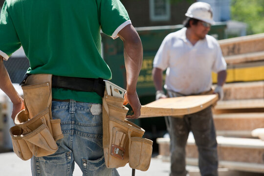 Carpenters lifting laminated beams at a construction site