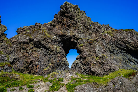 Natural rock arch formation with green moss and blue sky background,Dj&uacute;pal&oacute;nssandur,Iceland