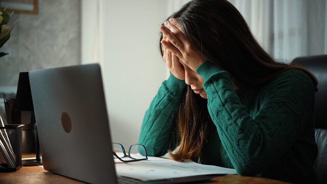 Young secretary feeling frustrated and stressed in her office due to long working hours. Workplace stress, burnout and employee wellbeing concept.