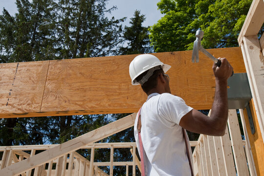 Carpenter hammering a beam in place