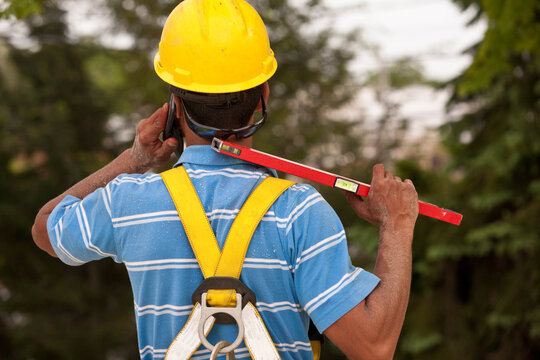 Carpenter holding a level and talking on a mobile phone