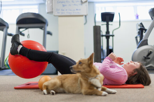 Woman with Down Syndrome working out on a yoga mat with her dog