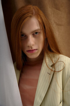 Handsome young man with long red hair showcasing elegance in stylish attire