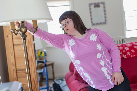 Girl with Down Syndrome turning on the light in her living room