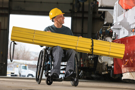 Maintenance supervisor with spinal cord injury preparing to load shielding onto utility truck