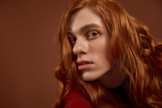 Elegant young man with flowing red hair showcases sophisticated fashion sense