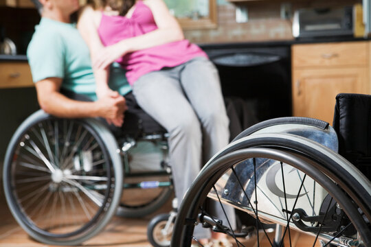 Woman sitting on the lap of a man in a wheelchair