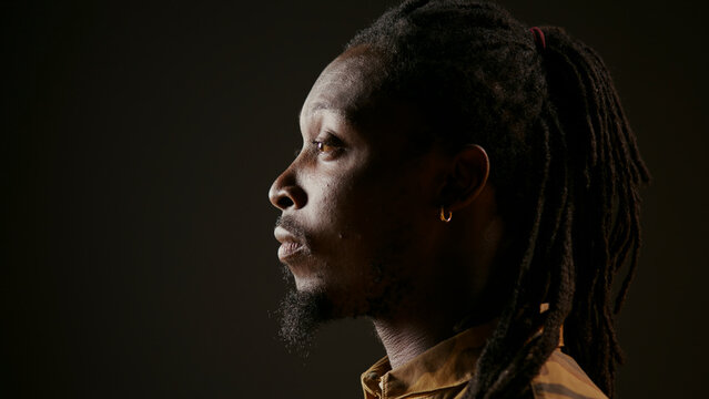 Stylish male model acting surprised and amazed by view, seeing something and being shocked. African American guy admiring a thing and saying wow in studio with black background.