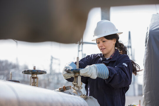 Female power engineer adjusting water valves at power plant
