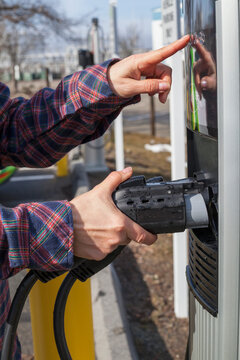Woman preparing to use charging station for electric vehicle
