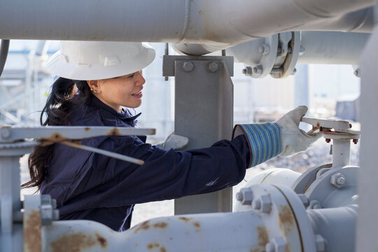 Female power engineer adjusting pressure valve at power station