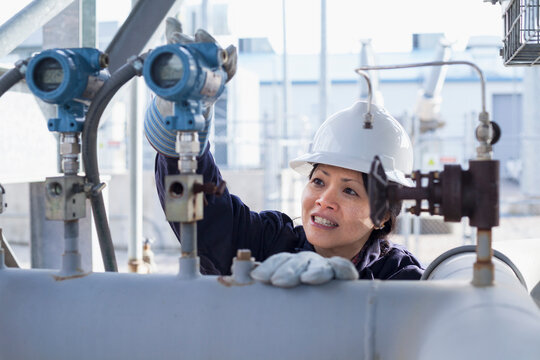 Female power engineer checking pressure transducers at power plant