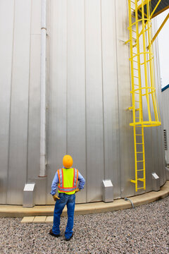 Engineer at electric power plant standing near water storage tank