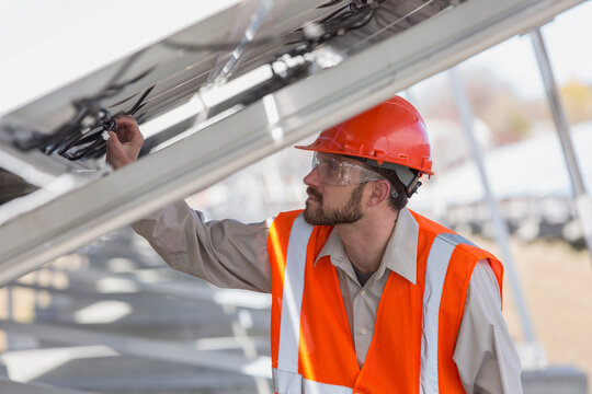 Power engineer at solar photovoltaic array examining the connections of panels